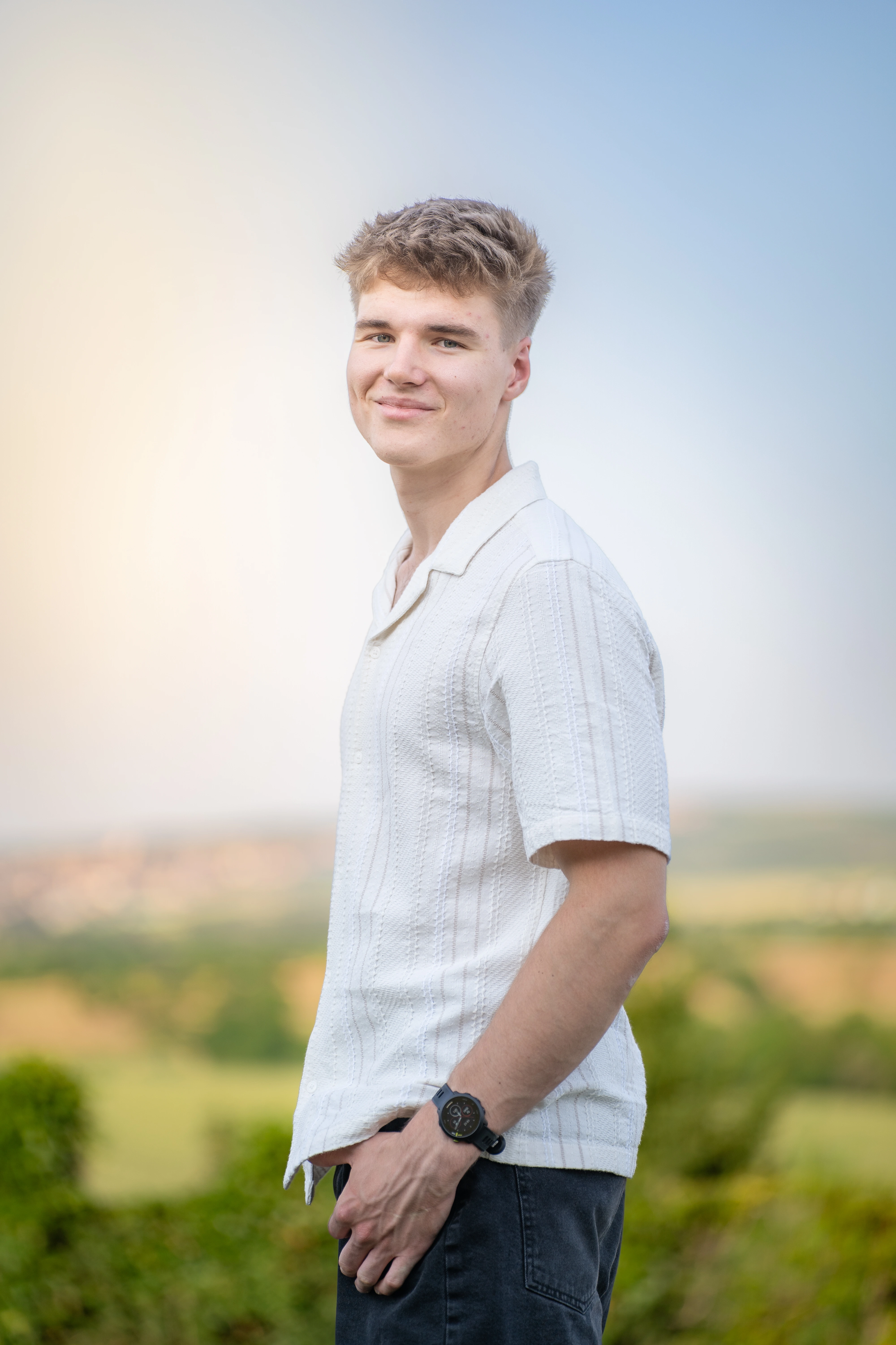 Portrait of Kamil Vítek outdoors in a cream shirt against a soft field background